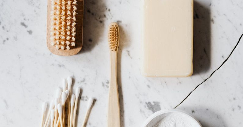 Natural Cleaning Products - Top view composition of wooden cleaning brush and soap and toothbrush and tooth powder and cotton swab placed on marble surface with line chip