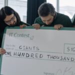 Grants - Team Holding a Big Check Happy About Winning Additional Funding