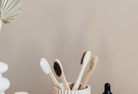 Sustainable Alternatives - Collection of bamboo toothbrushes and organic natural soaps with wooden body brush arranged with recyclable glass bottle with natural oil and ceramic vase with artificial plant