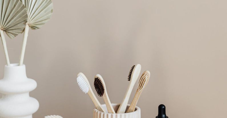 Sustainable Alternatives - Collection of bamboo toothbrushes and organic natural soaps with wooden body brush arranged with recyclable glass bottle with natural oil and ceramic vase with artificial plant